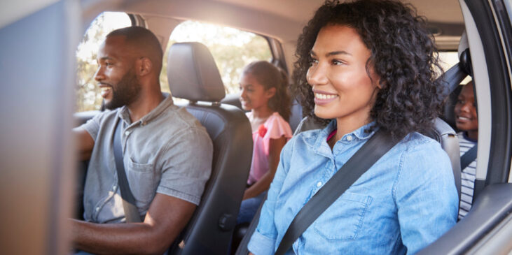 Young happy family with children in a car going on road trip
