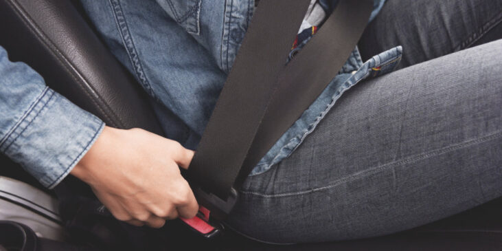 Female hands fasten the seat belt in the car. Conception of safe driving