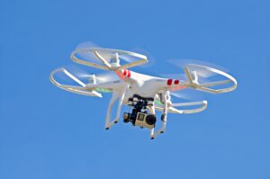 An image of a white drone in flight against a backdrop of a clear blue sky