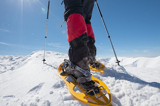 Hiker snowshoeing in winter mountains during sunny day