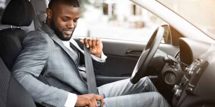 Image of man in a suit fastening his seat belt in his car, ready to go to office