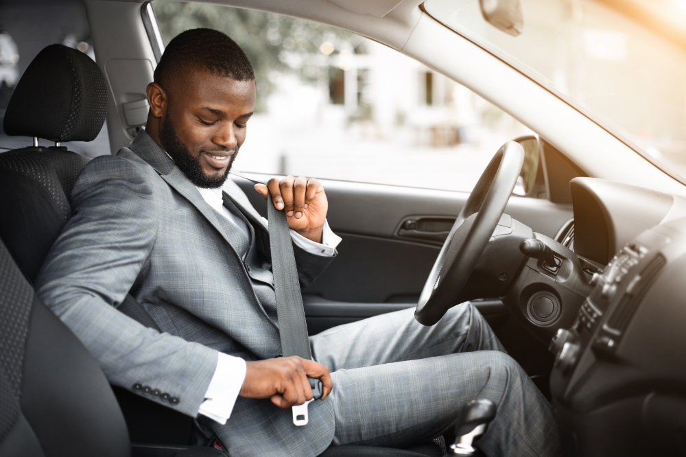 Image of man in a suit fastening his seat belt in his car, ready to go to office